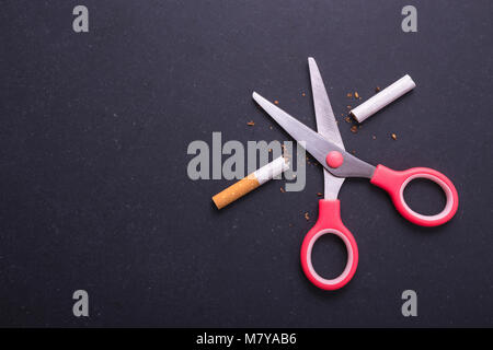 Rauchen aufhören Konzept. Rosa scissor cut Zigarette im Sinne stoppen. Ansicht von oben auf dem Schwarzen Brett Hintergrund Stockfoto