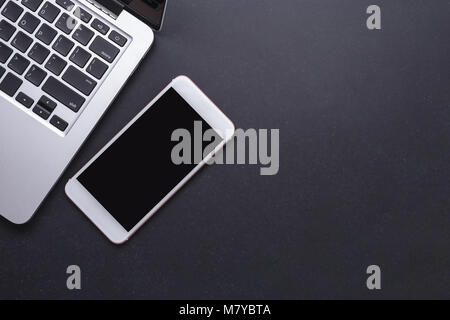 Moderne Smartphone und Laptop auf schwarzen Stein Tabelle Vorstand Hintergrund. Ansicht von oben mit Platz für Text oder Design Stockfoto