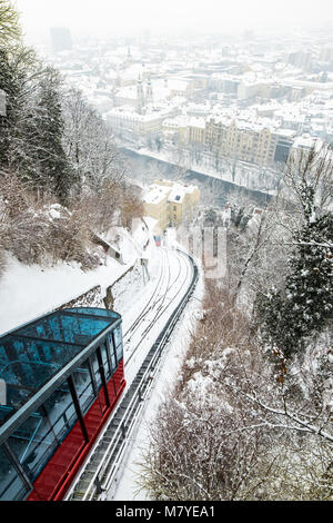 Rote Seilbahn Seilbahn auf Berg Schlossberg mit Blick auf verschneite Stadt Graz im Winter Stockfoto