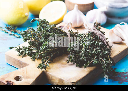 Bündel von Thymian, frischer Zitronen und Knoblauch auf Holz Schneidebrett. Zutaten der traditionellen mediterranen Küche Stockfoto