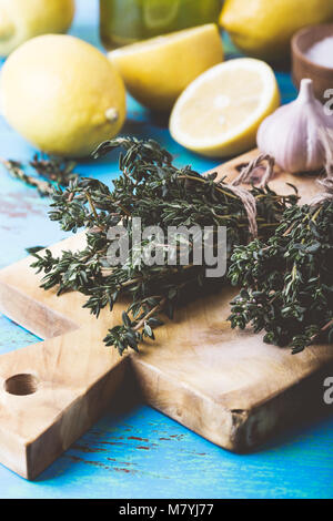 Bündel von Thymian, frischer Zitronen und Knoblauch auf Holz Schneidebrett. Zutaten der traditionellen mediterranen Küche Stockfoto