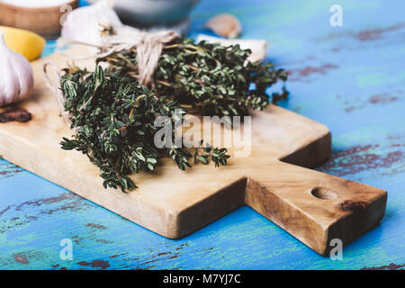 Bündel von Thymian, frischer Zitronen und Knoblauch auf Holz Schneidebrett. Zutaten der traditionellen mediterranen Küche Stockfoto