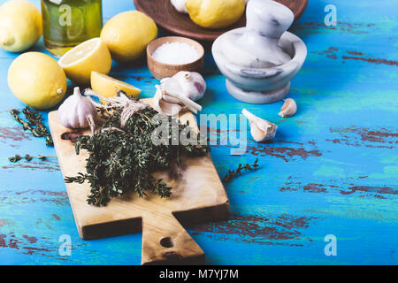 Bündel von Thymian, frischer Zitronen und Knoblauch auf Holz Schneidebrett. Zutaten der traditionellen mediterranen Küche Stockfoto