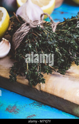 Bündel von Thymian, frischer Zitronen und Knoblauch auf Holz Schneidebrett. Zutaten der traditionellen mediterranen Küche Stockfoto