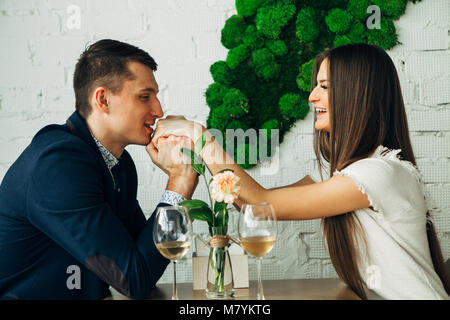 Fröhlicher junger Mann und Frau sind dating im Restaurant. Sie sitzen am Tisch und an einander mit der Liebe. Stockfoto