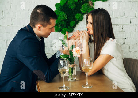 Fröhlicher junger Mann und Frau sind dating im Restaurant. Sie sitzen am Tisch und an einander mit der Liebe. Stockfoto