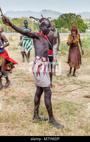 Ein Hamar Tribesman bereitet die Peitsche Junge Hamar Frauen während einer 'Erwachsen' Stier springen Zeremonie, Dimeka, Omo Valley, Äthiopien Stockfoto