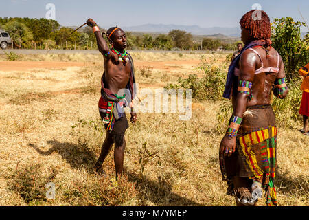 Ein männlicher Hamar Hamar Tribesman Peitschen junge Frauen während einer 'Erwachsen' Stier springen Zeremonie, Dimeka, Omo Valley, Äthiopien Stockfoto