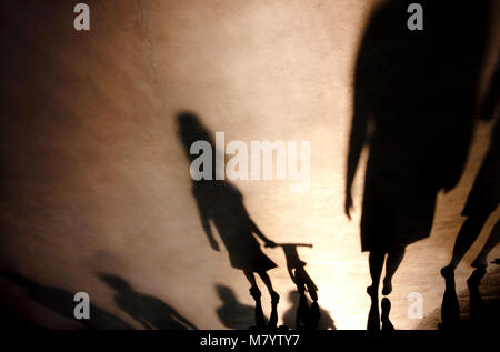 Verschwommene Schatten Silhouetten der Familie mit einem kleinen Mädchen drücken Fahrrad auf misty Sommer promenade Stockfoto