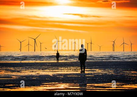 Sonnenuntergang über der Irischen See bei Crosby, Merseyside. März 2018. Wetter in Großbritannien. Nach einem schönen Frühlingstag mit Sonnenschein und blauem Himmel, ruht ein atemberaubender Sonnenuntergang zwischen den Windturbinen-Propellern auf dem Windpark Burbo Bank und den Iron man-Strandlandschaften an einem anderen Ort vor der Küste in der Nähe von Crosby in Merseyside aus. Stockfoto