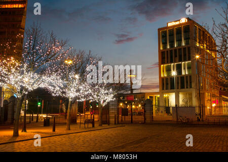 Albert Dock; Liverpool; Merseyside. 14. März 2018. Wetter in Großbritannien; farbenprächtiger Sonnenaufgang über der Uferpromenade der Stadt und Hilton Hotel. Am frühen Morgen schimmert die Sonne auf den Fenstern mit Reflexionen auf dem Schild und den Sehenswürdigkeiten der Stadt. Stockfoto