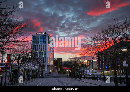 Albert Dock, Liverpool, Merseyside. 14. März 2018. UK Wetter; farbige Sonnenaufgang über der Stadt am Wasser. Am frühen Morgen Sonne funkeln auf dem Windows mit Reflexionen über Sehenswürdigkeiten der Stadt. Credit: MediaWorldImages/AlamyLiveNews. Stockfoto