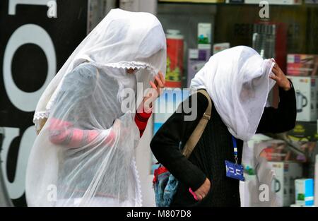 Srinagar, Indien. 14 Mär, 2018. Kaschmir Mädchen gehen gemeinsam unter dem Regen in Srinagar, Indien verwalteten Kaschmir. Die obere erreicht, darunter die weltberühmten Skigebiet Gulmarg, Schneefall, Regen peitschte Srinagar, und andere Teile des Kaschmir Tal. Eine westliche Störungen ist derzeit über den westlichen Himalaya Region die erwartet wird, Regen und Schneefall über Teile von Kaschmir in den nächsten Tagen zu geben. Credit: Saqib Majeed/SOPA Images/ZUMA Draht/Alamy leben Nachrichten Stockfoto