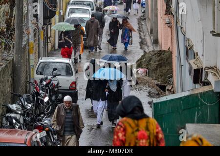 Srinagar, Indien. 14 Mär, 2018. Fußgänger halten Schirme gehen um an einem regnerischen Tag in Srinagar, Kashmir Indiann verabreicht. Die obere erreicht, darunter die weltberühmten Skigebiet Gulmarg, Schneefall, Regen peitschte Srinagar, und andere Teile des Kaschmir Tal. Eine westliche Störungen ist derzeit über den westlichen Himalaya Region die erwartet wird, Regen und Schneefall über Teile von Kaschmir in den nächsten Tagen zu geben. Credit: Saqib Majeed/SOPA Images/ZUMA Draht/Alamy leben Nachrichten Stockfoto