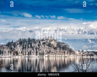 Der Bleder See mit Blick auf die Burg von Bled und Kirche des Asumption von Maria Bled Insel, gegen die majestätischen Alpen im Hintergrund, Aufwecken Stockfoto