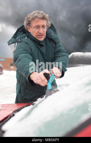 Bestimmt man Schaben Schnee und Eis von der Windschutzscheibe seines Autos midwinter in Vermont. Stockfoto