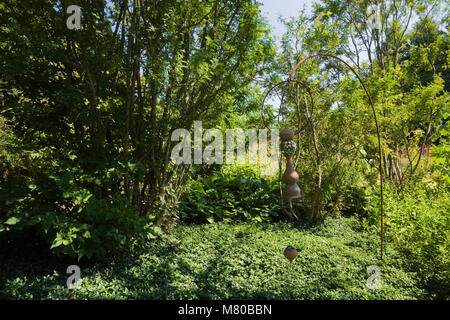 Dekorative Keramik Schmuck hängen von einem Stand in einem angelegten Garten im Hinterhof im Sommer Stockfoto