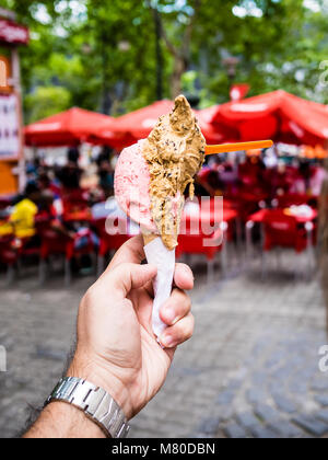 Zwei Kugeln Eis in der Hand gehalten, Stühle im Hintergrund Stockfoto