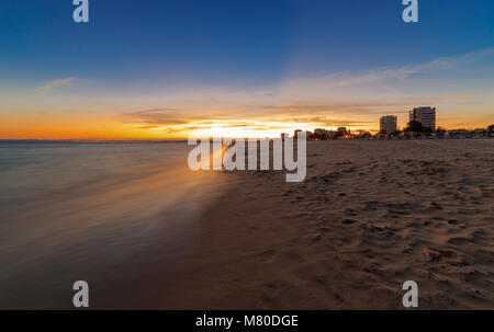 Sonnenuntergang auf der Praia dos Tres Irmaos - im Hintergrund die Stadt von Lagos Stockfoto