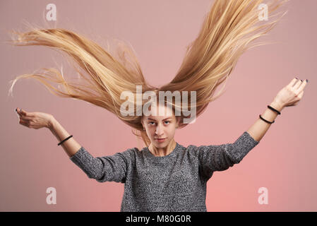 Portrait der junge blonde Frau mit Haar bis auf rosa Hintergrund isoliert Stockfoto