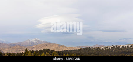 Seltsame Wolke über vom Schnee in den Bergen und Wäldern bedeckt Stockfoto