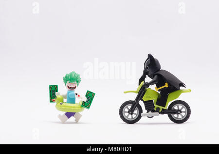 Lego Batman jagt Joker mit Geld, auf weißem Hintergrund. Stockfoto