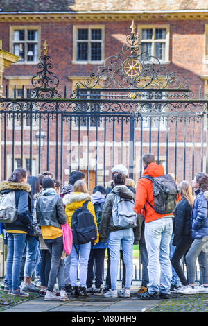 Eine Gruppe von Schülern (auf einer geführten Tour) vor dem Haupttor in St. Catherine's College, Universität Cambridge, an einem sonnigen Wintertag. Stockfoto