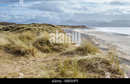 UK, Anglesey, Rhosneigr, 11. März 2018. Ein Blick entlang Llanddwyn Beach in Richtung der Menai Strait und Snowdonia. Stockfoto