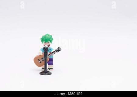 Lego joker Figur Holding eine Gitarre mit Mikrofon auf weißem Hintergrund. Stockfoto