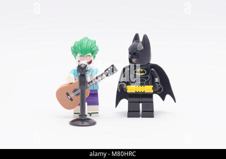 Lego Joker holding eine Gitarre mit Batman neben ihn beobachtete. auf weißem Hintergrund isolieren. Stockfoto