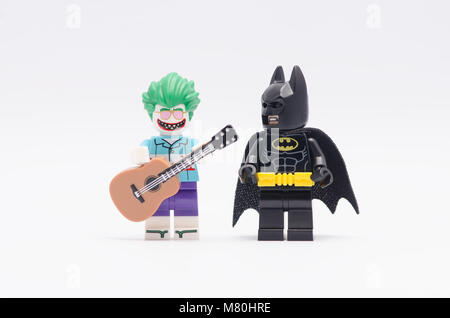 Lego Joker holding eine Gitarre mit Batman neben ihn beobachtete. auf weißem Hintergrund isolieren. Stockfoto