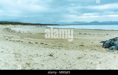 UK, Anglesey, Rhosneigr, 11. März 2018. Ein Blick auf llanddwyn Beach und die Berge von Snowdonia. Wanderer in der Ferne. Stockfoto