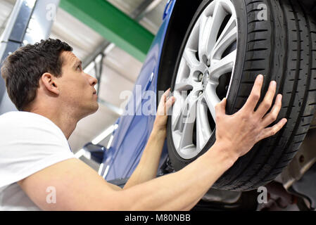 Reifenwechsel in der Werkstatt - Assembler in Arbeitskleidung Stockfoto