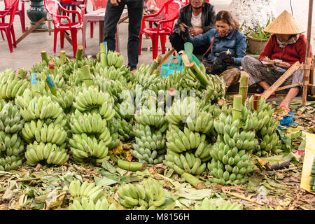 Eine Frau verkauft Bananen auf der Straße vor der Markthalle in Hoi An, Vietnam Stockfoto