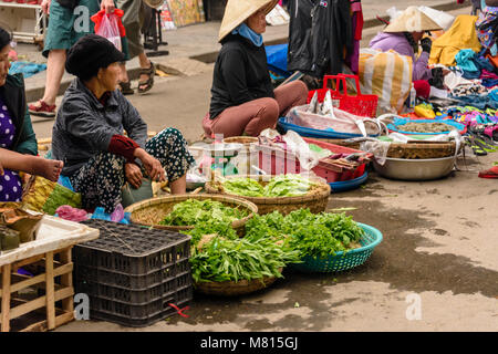 Eine Frau verkauft grünes Blattgemüse auf der Straße vor der Markthalle in Hoi An, Vietnam Stockfoto