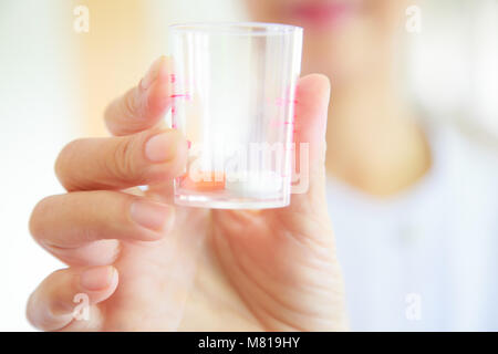 Weibliche Pflegekraft oder Arzt in weißem Kleid einheitliche Holding Pillen in der medizinischen Cup. Gesundheit, Medizin und professionellen Spezialisten für medizinische Dienste anhand von quantitativen Simulatio Stockfoto