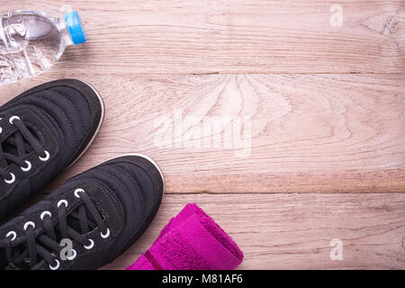 Schwarz läuft/Sneaker Schuh, Wasserflasche und Handtuch auf braun Holzboden. Übung Konzept. Ansicht von oben Stockfoto