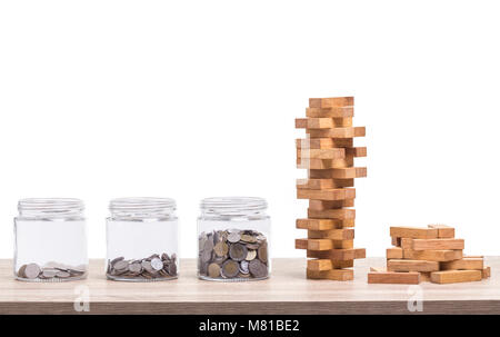 Stapel der Bausteine Holz Spiel und jar von Münze Sparschwein auf hölzernen Tisch. Studio geschossen und auf weißem Hintergrund Stockfoto