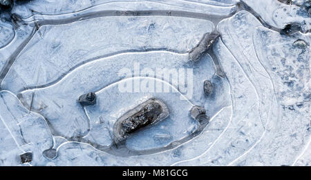 Schlammloch über mit weißen Eiskristallen, Ringe gefroren, und Felsen sichtbar Stockfoto