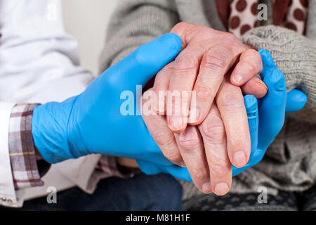 Close up Arzt trägt blaue Handschuhe halten ältere Frau die Hände schütteln, Parkinson Krankheit Stockfoto