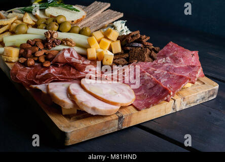 Aus Fleisch und Käse auf einem Schneidebrett sortiert. Geräucherte Wurst, Fleisch aus der Türkei mit Käse, Schinken, Oliven, Nüsse und verschiedene sorten Käse. Low Key. Dunklen Hintergrund Stockfoto