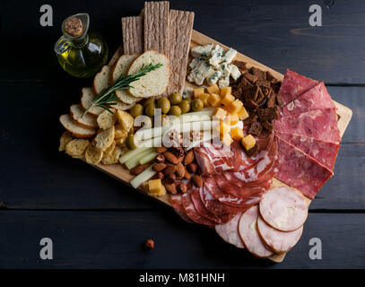Aus Fleisch und Käse auf einem Schneidebrett sortiert. Geräucherte Wurst, Fleisch aus der Türkei mit Käse, Schinken, Oliven, Nüsse und verschiedene sorten Käse. Mediterrane traditionelle Snacks. Ansicht von oben Stockfoto