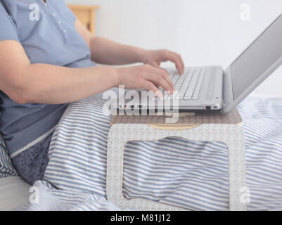 Frau arbeiten mit Laptop im Bett Stockfoto