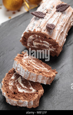 Yule Kuchen mit Schokolade Blätter auf einem Weihnachten Tabelle eingerichtet Log Stockfoto
