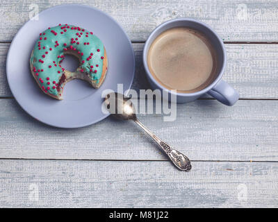Donut mit bunten Vereisung und Tasse Kaffee auf einer hölzernen Hintergrund Stockfoto