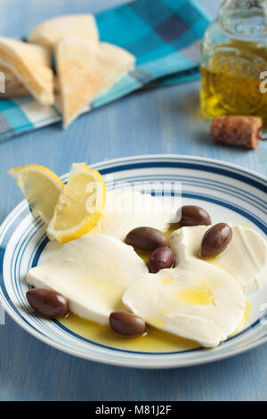 In Scheiben geschnittenen Mozzarella mit kalamata Oliven, Olivenöl, Zitronenscheiben und pita auf einer blauen Tabelle Stockfoto