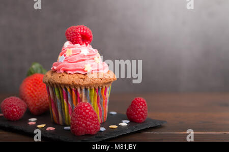 Selbst gebackene Muffins mit bunten Zuckerguss und Obst Nahaufnahme Stockfoto