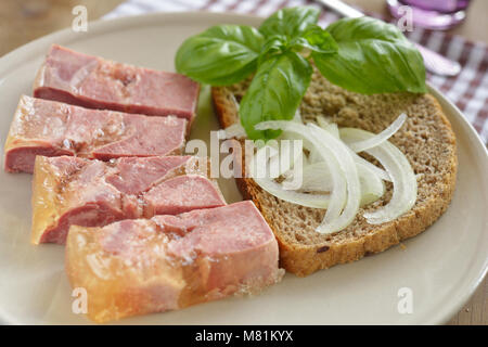 Rinderzunge in Aspik mit Basilikum und Zwiebeln auf der Scheibe Brot Stockfoto