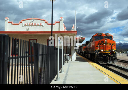 Ein Güterzug Rumpelt vorbei an der restaurierten Railroad Depot in Kingman, Arizona, im Jahre 1907 erbaut und im Jahr 2011 wieder geöffnet nach einer längeren Rehabilitation. Stockfoto