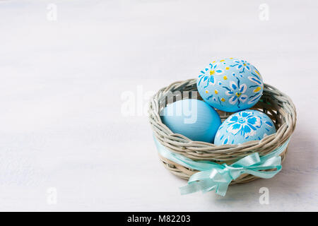 Ostern Hintergrund mit Hellblau bemalte Eier in der kleinen Weidenkorb mit Seidenband. Frohe Ostern Grußkarte, kopieren. Stockfoto